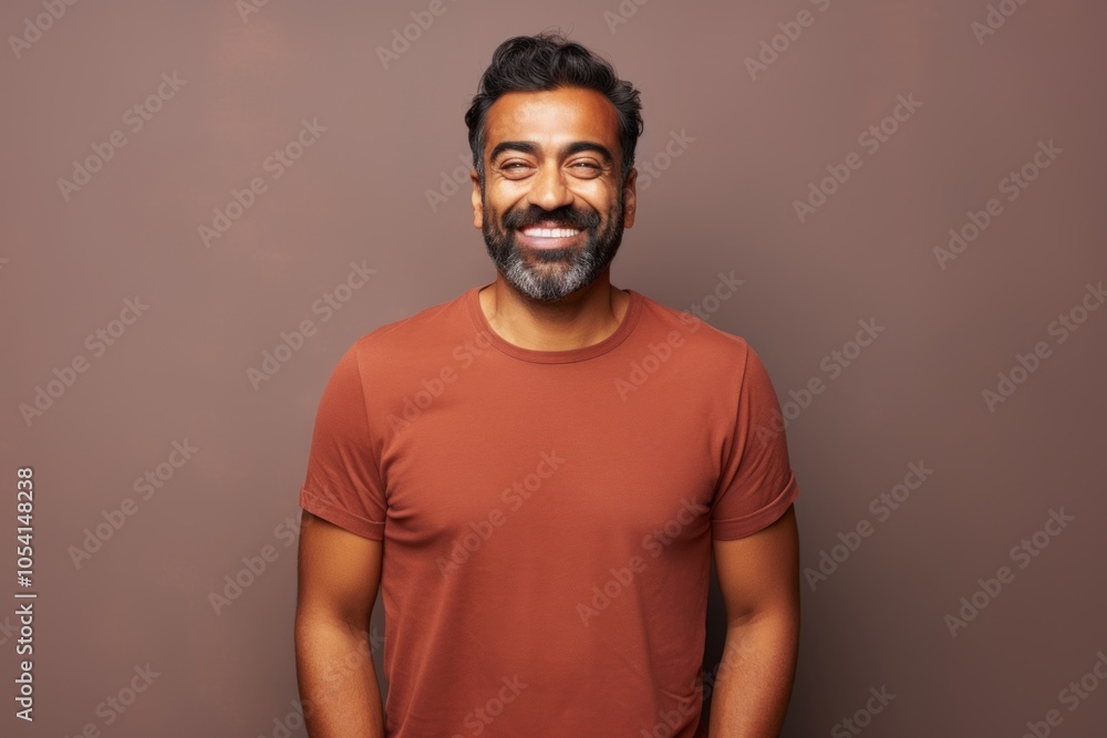 Obraz premium Portrait of a satisfied indian man in his 30s donning a trendy cropped top on solid color backdrop