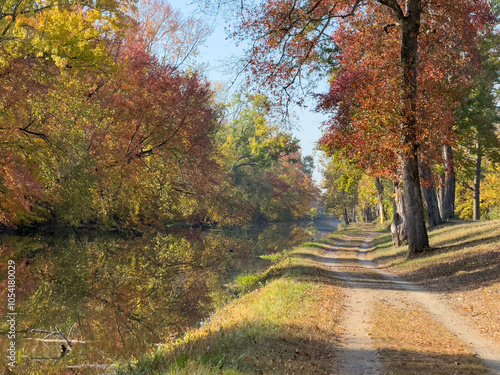 Beautiful autumn colors at Delaware and Raritan Canal Park in Princeton, New Jersey. Peaceful scenery with fallen leaves, trees reflection, and beautiful fall colors