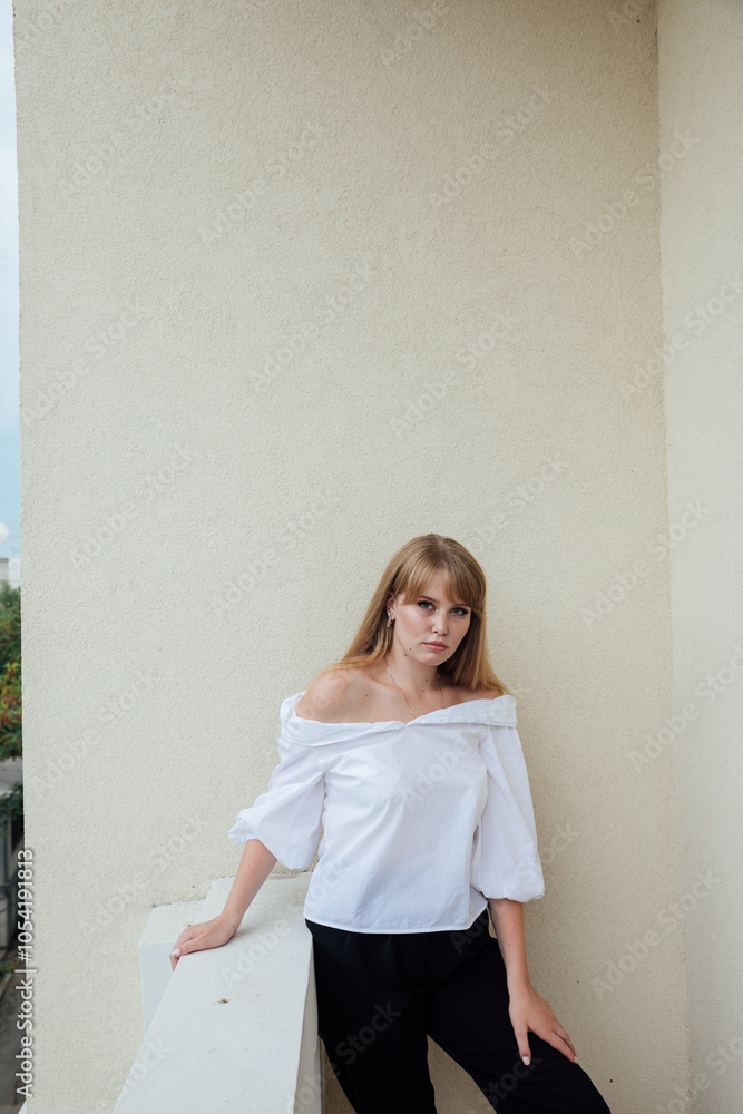 Fototapeta premium Portrait of a beautiful young woman in a white blouse and black pants