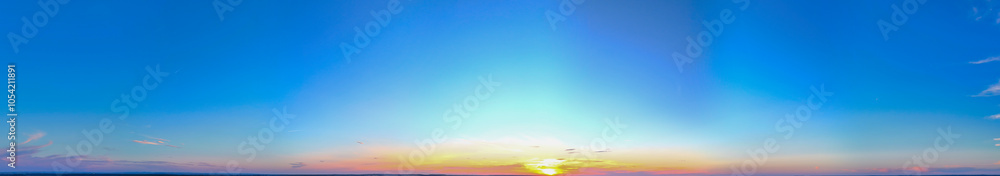 Obraz premium A stunning panoramic view of a colorful sunset, featuring vibrant hues of orange, yellow, and blue. Ideal for nature lovers and those seeking serene landscapes.
