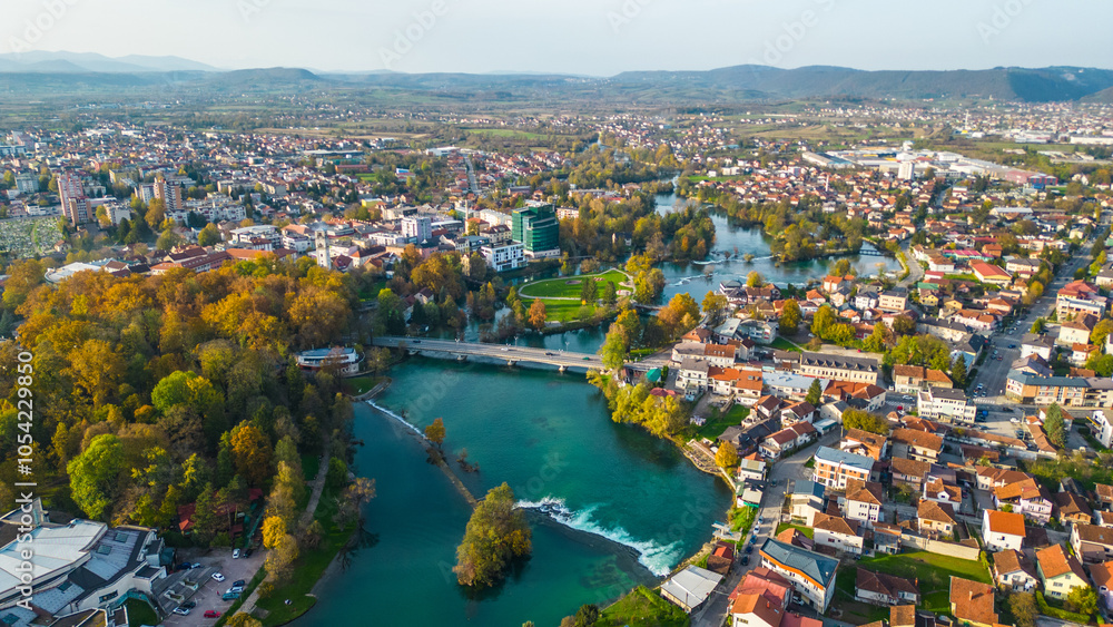 Fototapeta premium Bihać, a picturesque city in Bosnia, showcases vibrant autumn colors along the pristine River Una. The natural beauty of the area is accentuated by the golden and amber leaves that frame the riverbank