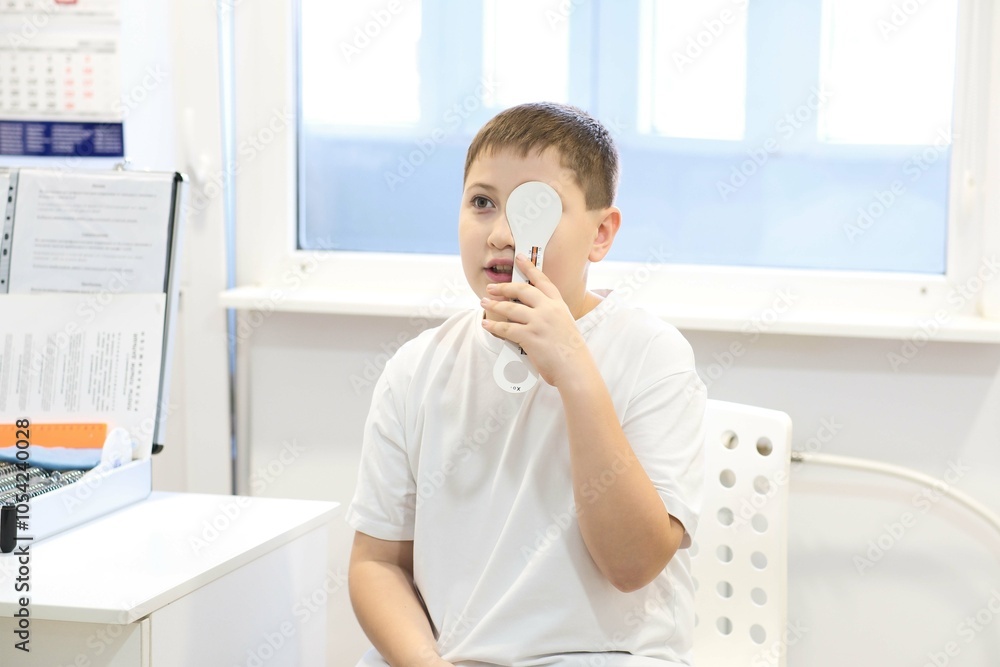 Fototapeta premium Boy doing eye test checking examination with optometrist in optics store, kid boy choosing eyeglasses in optics store