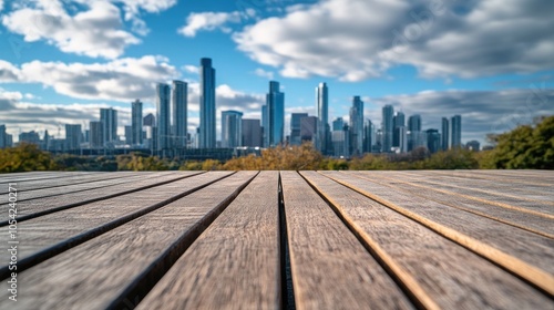 A wooden deck in the foreground with a city skyline under a cloudy sky.