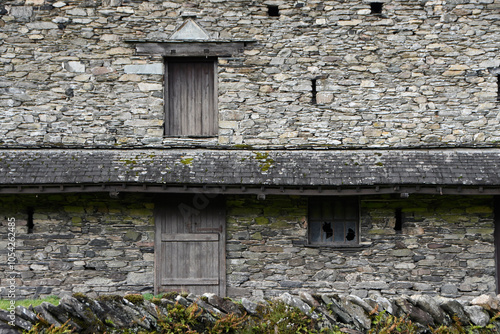 The side of an old stone barn with closed doors and windows in Keswick in the Lake District