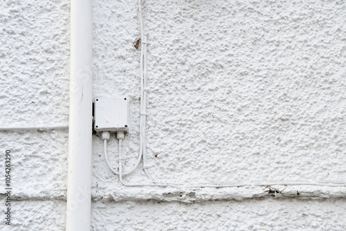 White cables and drain pipes on the exterior of a white pebble dashed house photo