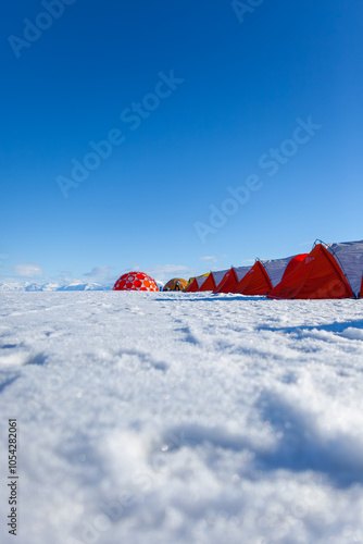 Bright Tents on Snowy Landscape Under Clear Blue Sky
