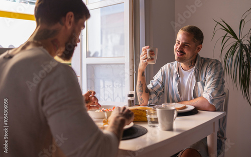 Gay couple enjoying breakfast and coffee together at home photo