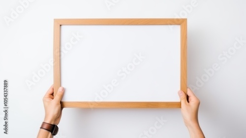 Hands grasp a blank wooden picture frame against a plain white background, inviting potential for creative expression and personalization.