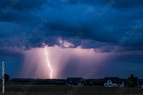 A huge storm cloud with a wall of rain in the countryside and big lightning.

