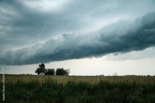 A huge storm cloud with a wall of rain in the countryside and big lightning.
