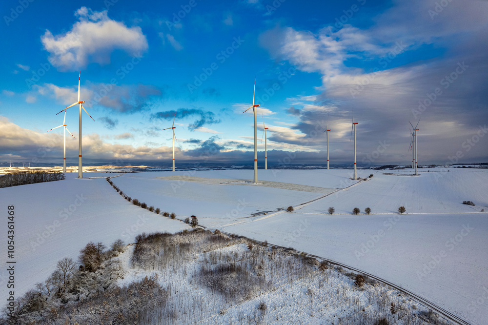 Drone shot of wind turbines in late afternoon light in flat snowy northern German landscape