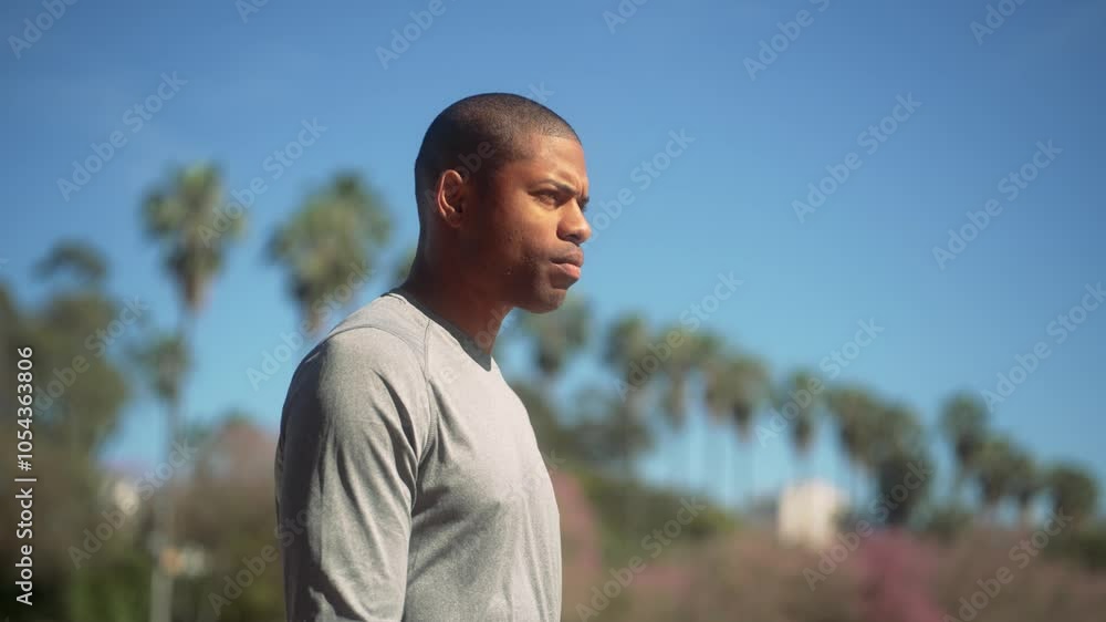 Focused African American man warming up by rotating his shoulder and neck outdoors on a sunny day. Athletic male in fitness clothes preparing for exercise with stretching movements Focused African American man warming up by rotating his shoulder and neck outdoors on a sunny day. Athletic male in fitness clothes preparing for exercise with stretching movements
