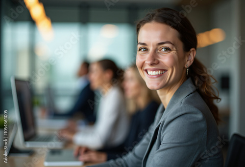 businesswoman smiles office meeting colleagues looking directly camera