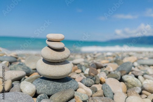 Pebble grey stones on top of each as pyramid or heap on seashore with acean water.Metaphor of calmness, harmony and tranquility, stress photo