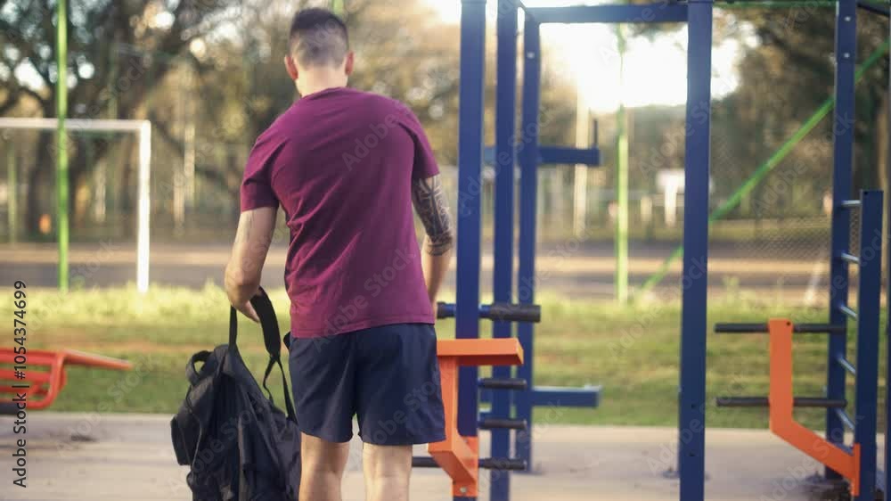 Man arriving at outdoor gym with athletic gear and water bottle. Individual in activewear starting a workout session at a public park, preparing for exercise. Man arriving at outdoor gym with athletic gear and water bottle. Individual in activewear starting a workout session at a public park, preparing for exercise.