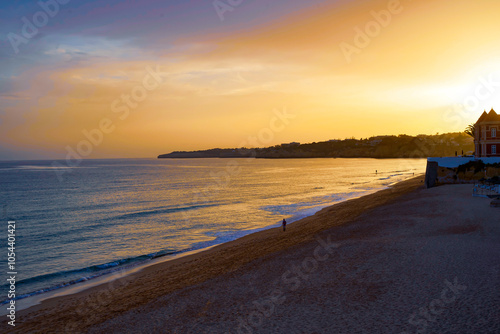 Golden Sunset over tranquil Beach with calm Waves and expansive horizon, casting warm light over the Sea and Sand. Copy Space 