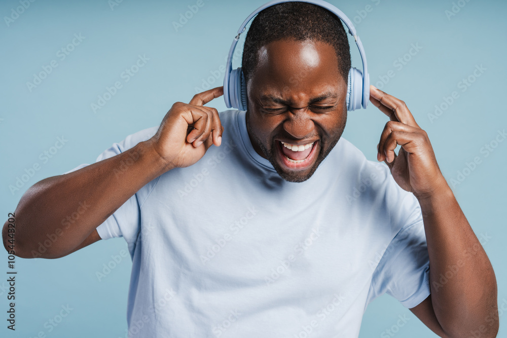 Naklejka premium African American man with closed eyes wearing wireless headphone enjoying music