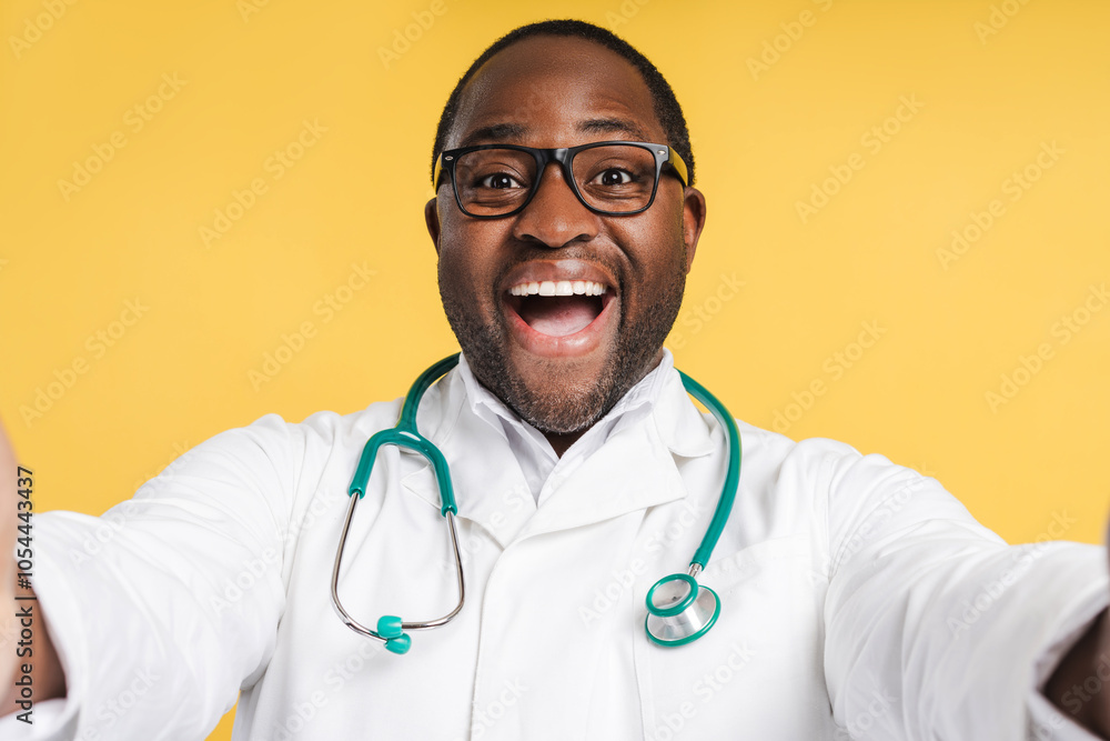 Smiling African American man with stethoscope and glasses, wearing white coat in studio Smiling African American man with stethoscope and glasses, wearing white coat in studio