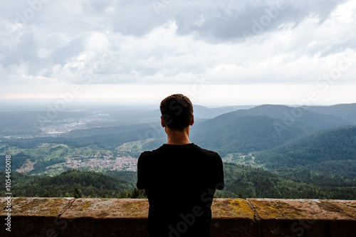 Mann schaut von einem Turm über Wald und Dörfer bei trüben Wetter photo