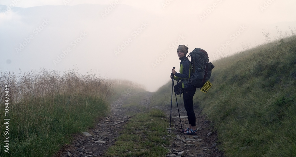 A young girl travels, is engaged in active sports, climbs with trekking poles in atmospheric weather, the slopes of the mountains and the forest A young girl travels, is engaged in active sports, climbs with trekking poles in atmospheric weather, the slopes of the mountains and the forest