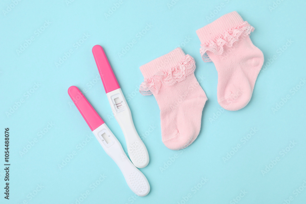 Pregnancy tests and pink socks on light blue background, top view Pregnancy tests and pink socks on light blue background, top view