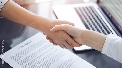 Business people shaking hands above contract papers just signed on the white table, closeup. Lawyers at meeting. Teamwork, partnership, success concept