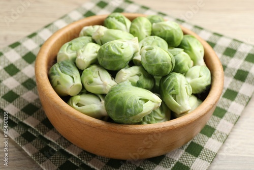 Fresh green Brussels sprouts in bowl on wooden table, closeup