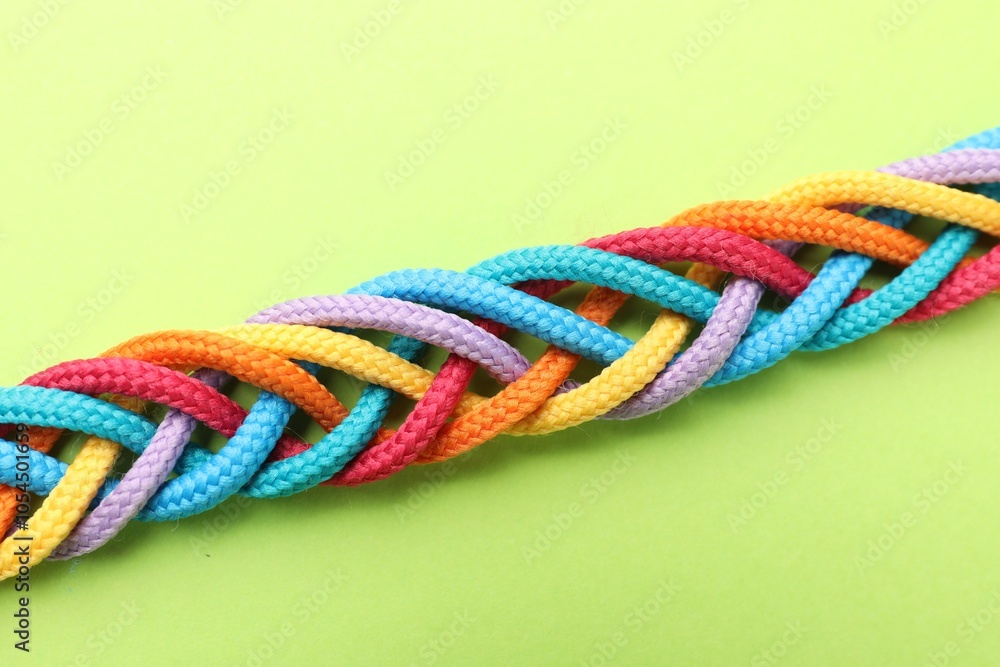 Braided colorful ropes on light green background, top view. Unity concept Braided colorful ropes on light green background, top view. Unity concept