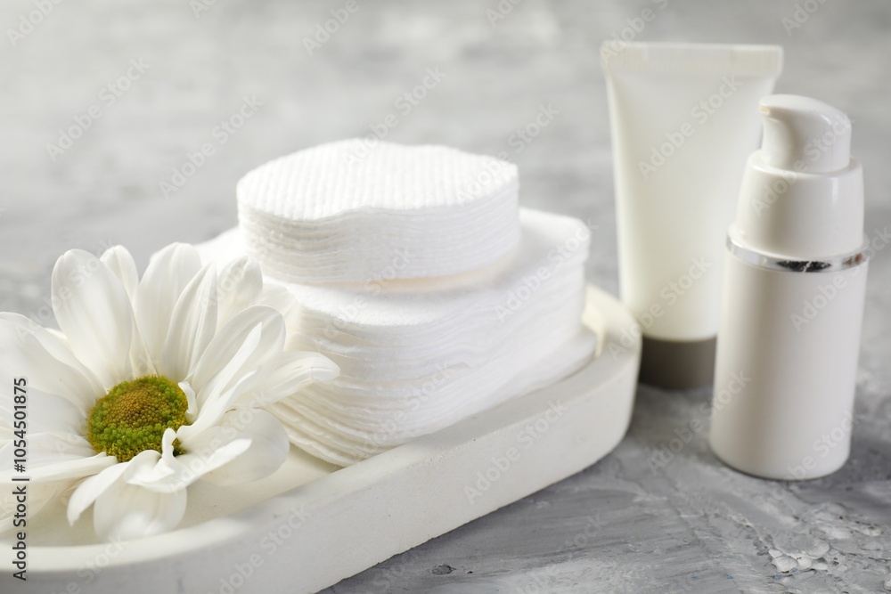 Clean cotton pads, cosmetic products and flower on grey table, closeup Clean cotton pads, cosmetic products and flower on grey table, closeup