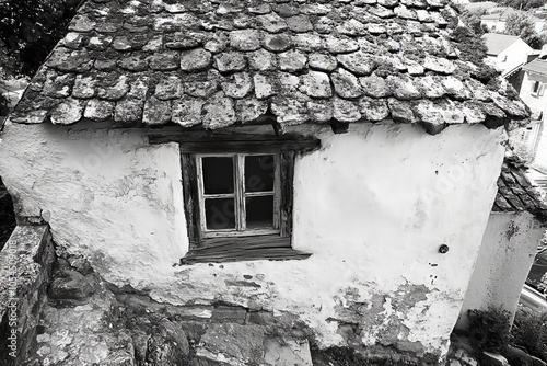 Weathered white stone cottage with tiled roof and rustic window evoking countryside charm simplicity and old world aesthetic suited for rural and historical themes photo