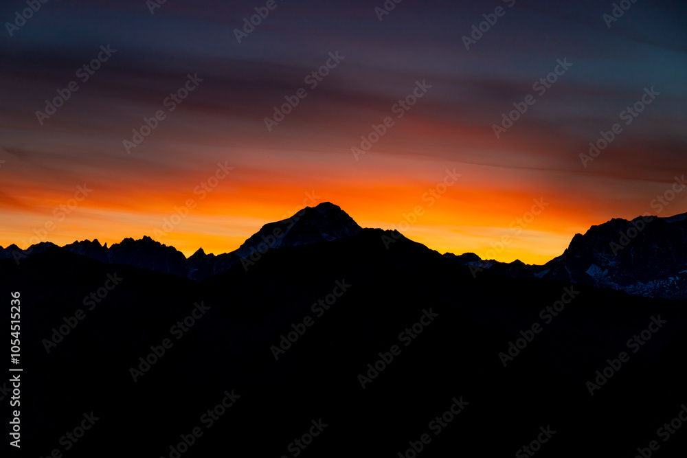 Sunset burning red and orange sky above the snow summits and rocky peaks of the Alps. Beautiful mountain sunset and sunrise in Chamonix valley on the ascent to Montblanc Sunset burning red and orange sky above the snow summits and rocky peaks of the Alps. Beautiful mountain sunset and sunrise in Chamonix valley on the ascent to Montblanc