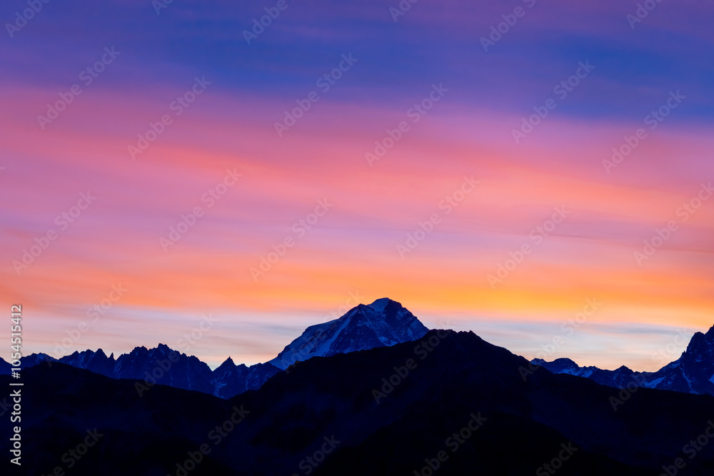 Obraz premium Sunset burning red and orange sky above the snow summits and rocky peaks of the Alps. Beautiful mountain sunset and sunrise in Chamonix valley on the ascent to Montblanc