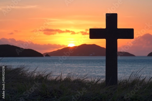 Dark cross silhouette stands solemnly at sunset on a hill by the sea evoking a sense of reverence solitude and peace against the radiant evening sky