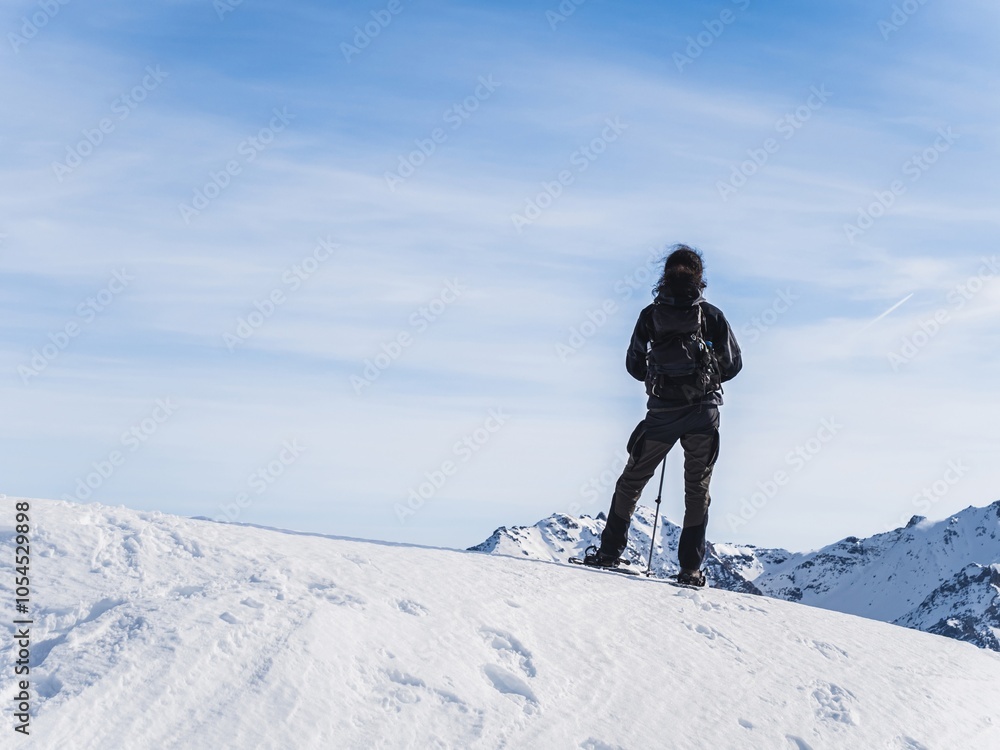 Snowshoer standing on snowy ridge in mountain landscape Snowshoer standing on snowy ridge in mountain landscape