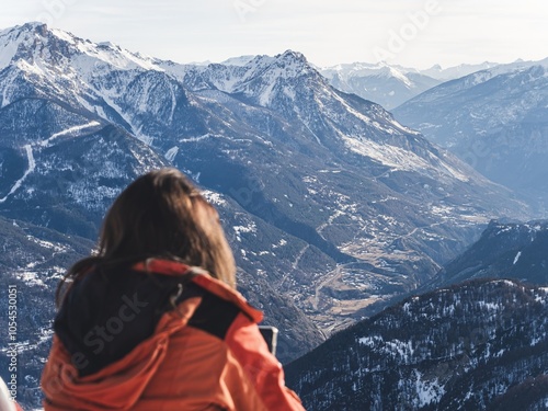 Woman enjoying mountain view in winter with smartphone photo