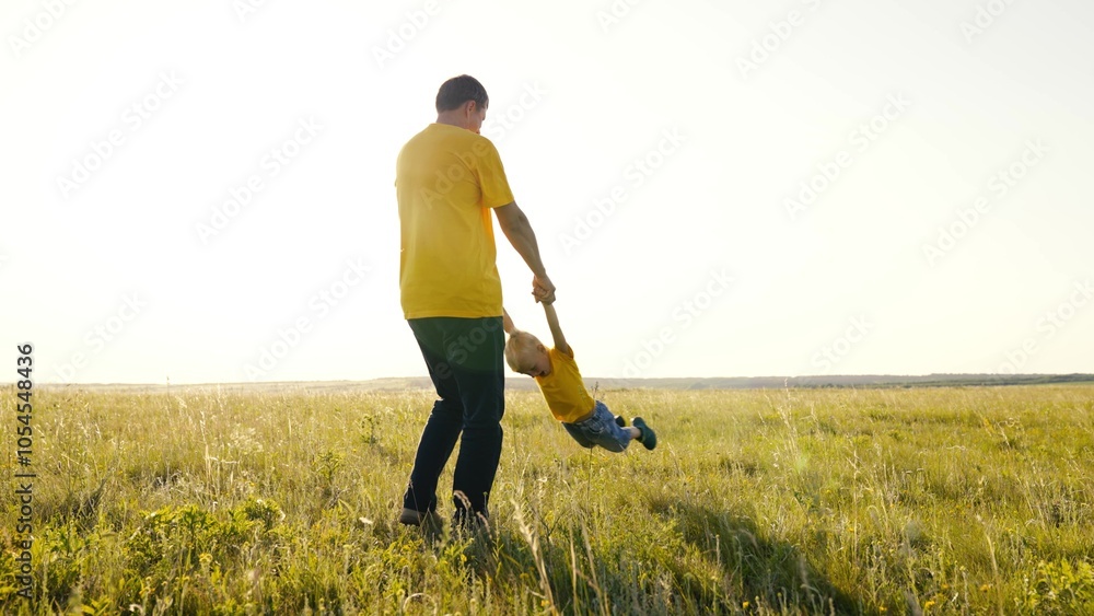 happy family. father circling boy son against backdrop white sky glare sun. happy family concept. little boy dreams of flying. boy superhero. father plays with child kid in flight pilot in the meadow happy family. father circling boy son against backdrop white sky glare sun. happy family concept. little boy dreams of flying. boy superhero. father plays with child kid in flight pilot in the meadow