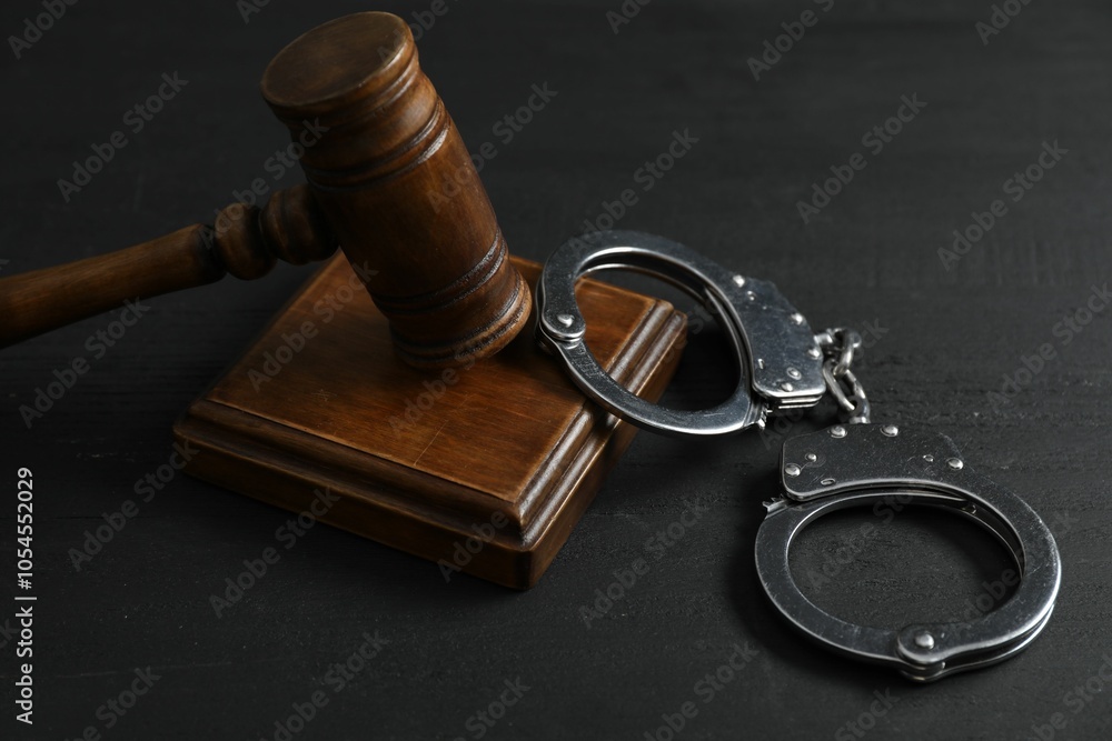 Handcuffs and judge's gavel on black wooden table, closeup Handcuffs and judge's gavel on black wooden table, closeup