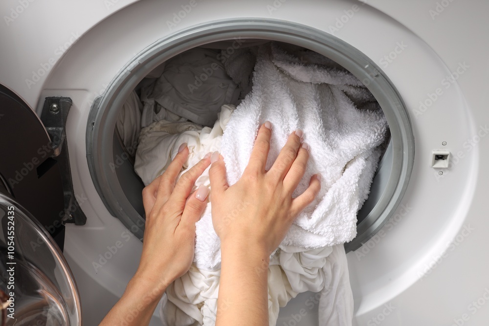 Woman taking clean clothes out of washing machine, closeup Woman taking clean clothes out of washing machine, closeup