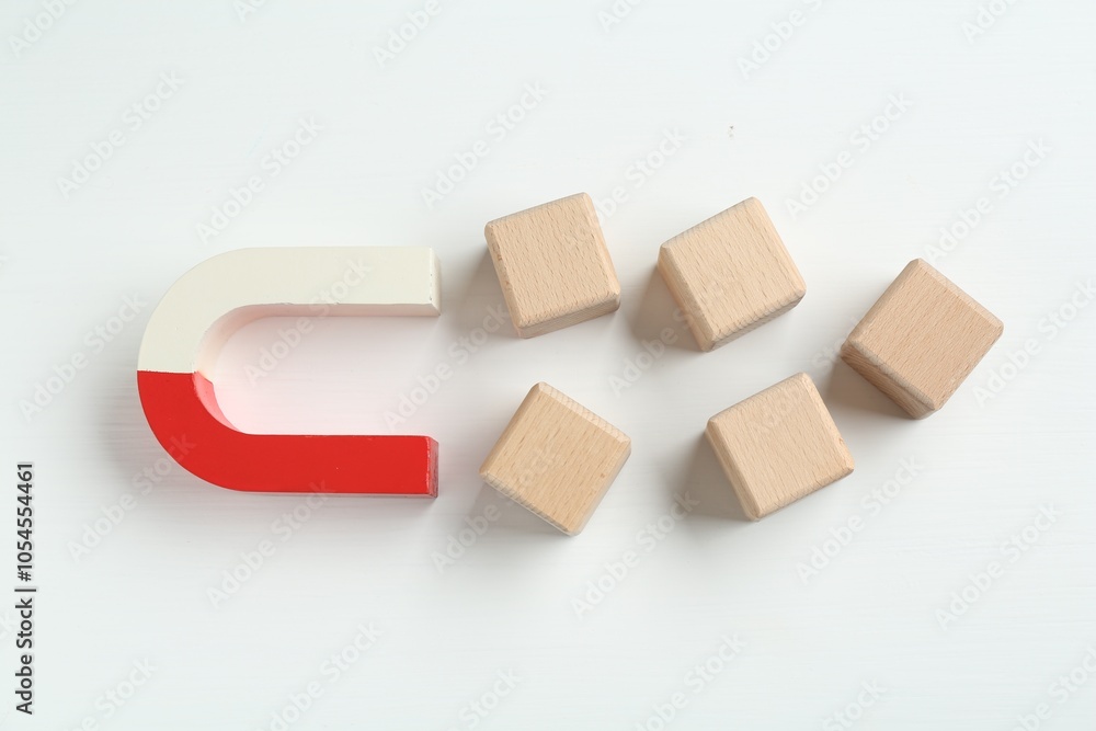 Magnet attracting wooden cubes on white background, flat lay Magnet attracting wooden cubes on white background, flat lay