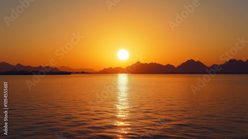 Golden sunset over tranquil waters with silhouetted mountains in the background