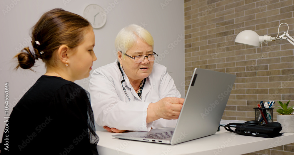 Woman doctor showing results to girl on laptop screen. Concept of medical, healthcare, healthy family, pediatric checkup and hospital office. Woman doctor showing results to girl on laptop screen. Concept of medical, healthcare, healthy family, pediatric checkup and hospital office.