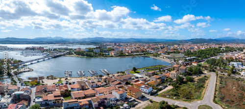 Tableau sur toile Aerial view of Olbia, Sardinia, showcasing a marina with boats, terracotta roofed buildings, a connecting bridge, and a mix of modern and traditional architecture