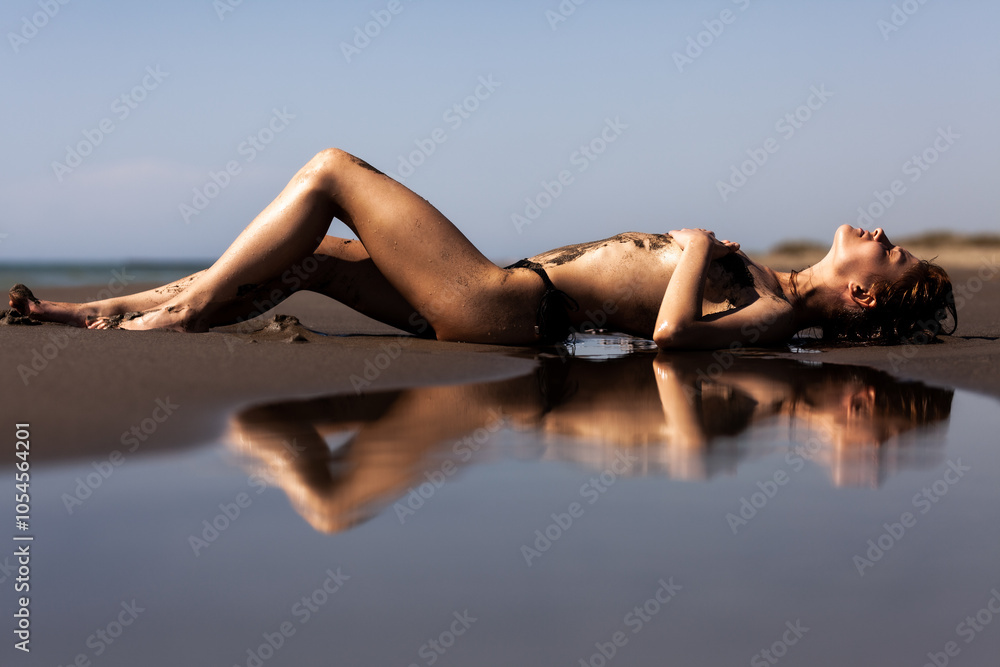 Sexy female body covered with sand. Girl on a beach with sea water reflection. . Sexy female body covered with sand. Girl on a beach with sea water reflection. .