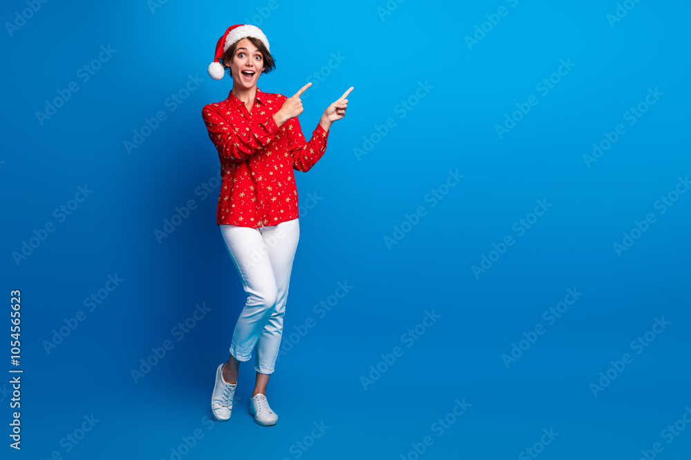 Full body portrait of nice young girl direct fingers empty space xmas new year holiday isolated on blue color background Full body portrait of nice young girl direct fingers empty space xmas new year holiday isolated on blue color background