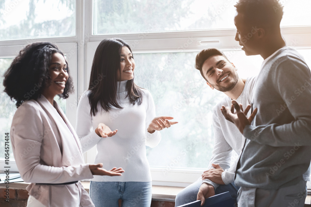 Cheerful multiracial young colleagues having small talk in office, office atmosphere concept Cheerful multiracial young colleagues having small talk in office, office atmosphere concept