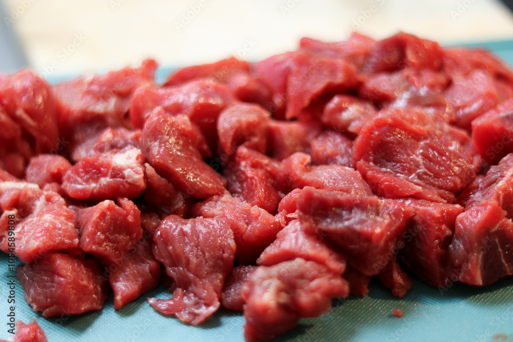 Close up of red raw beef meat chopped in small cubes on cutting board Close up of red raw beef meat chopped in small cubes on cutting board