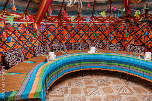 A colorful tent with a blue and green striped tablecloth, table for celebration in kyrgyz authentic yurt of nomads photo