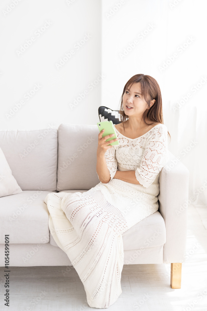 部屋でスマホを見る女性