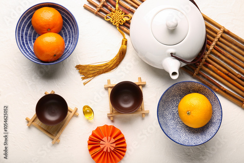 Teapot with cups, mandarins and oriental symbols on white grunge background. New Year celebration photo