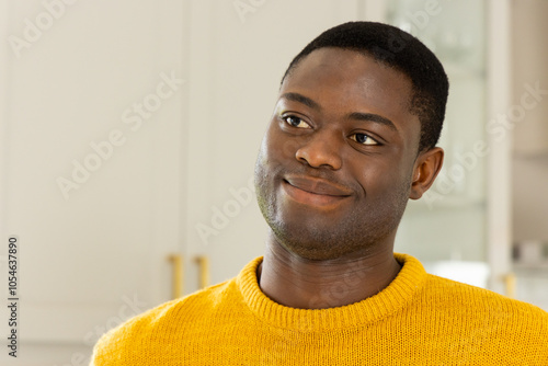 Smiling African american man in yellow sweater enjoying festive moment at home